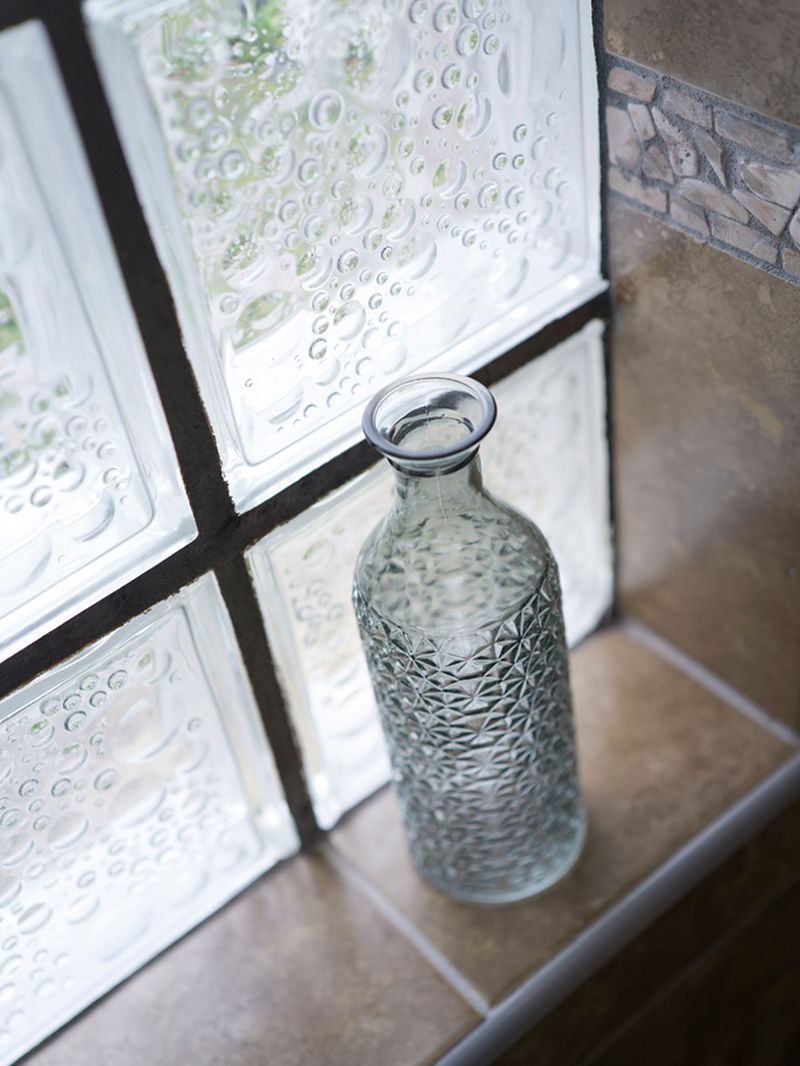 Glass carafe on a windowsill beside the cottage's original exposed stone wall