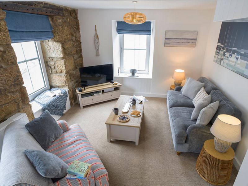 Open-plan sitting area for two with sofas, coffee table and coastal artwork