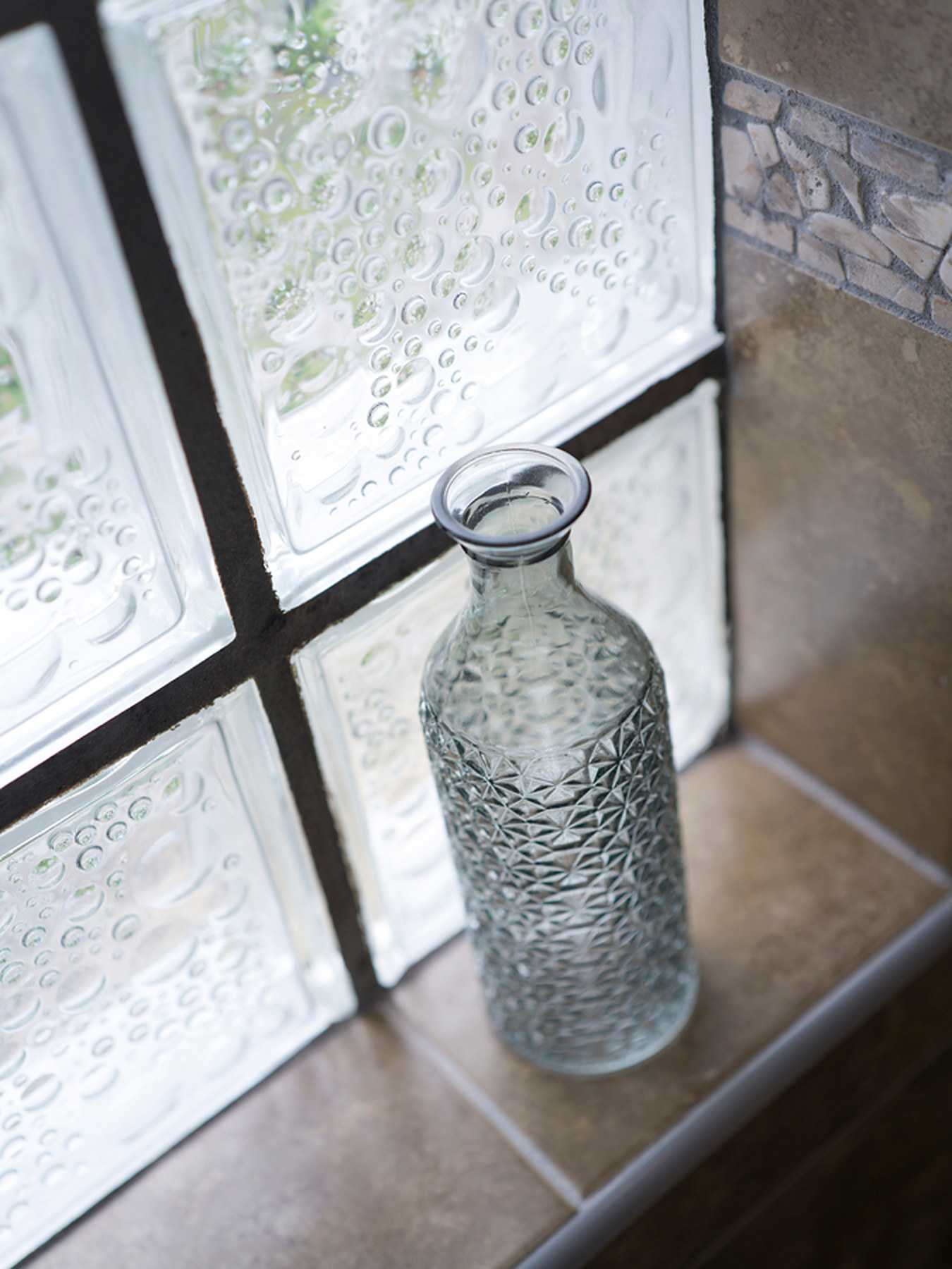 Glass carafe on a windowsill beside the cottage's stone wall