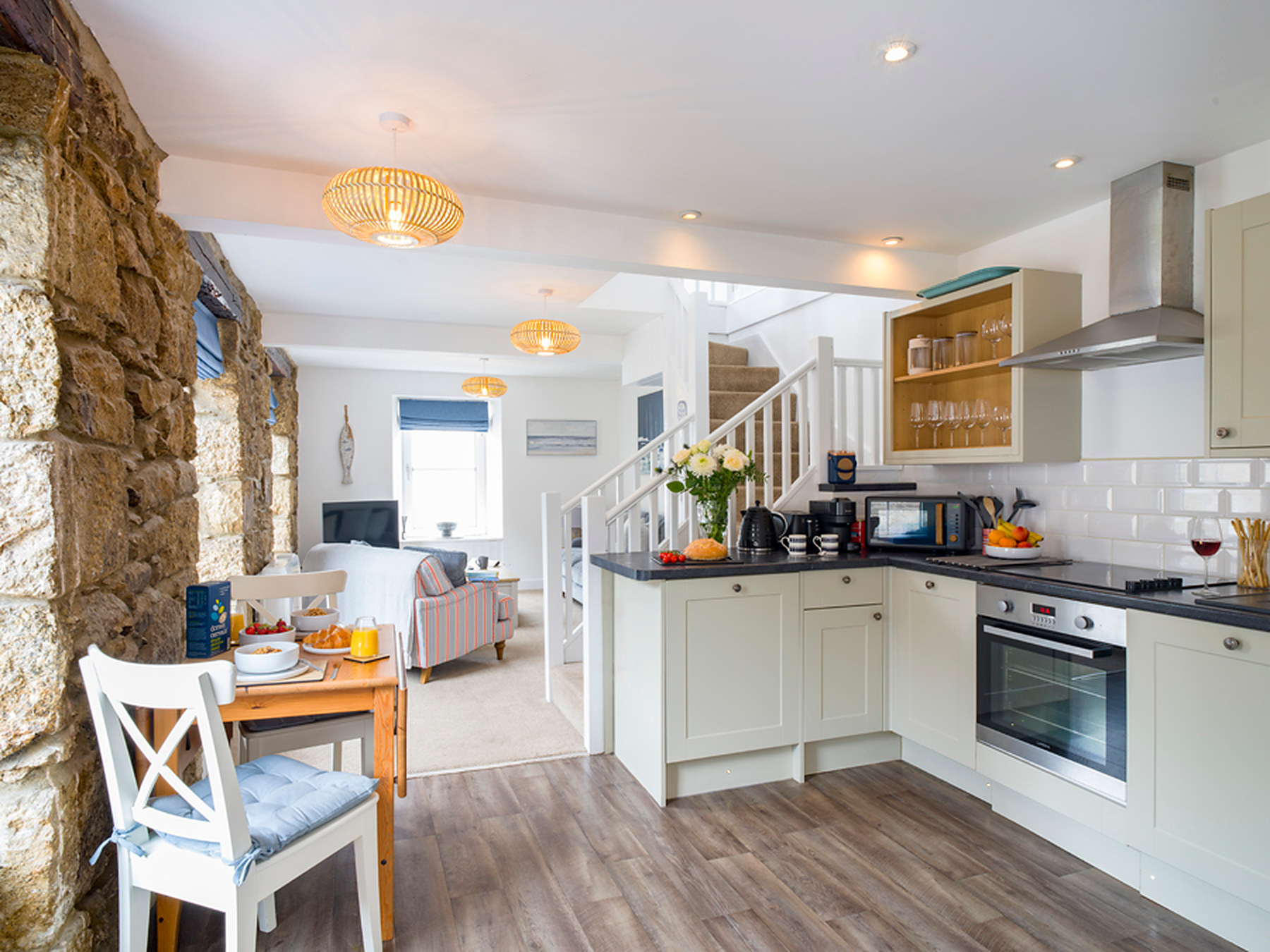 Open-plan ground floor looking past the stone wall to the kitchen and sitting area
