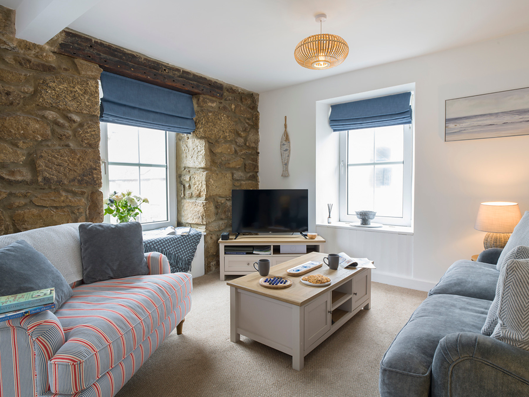 Sitting room with a striped sofa, snuggle chair and exposed stone wall