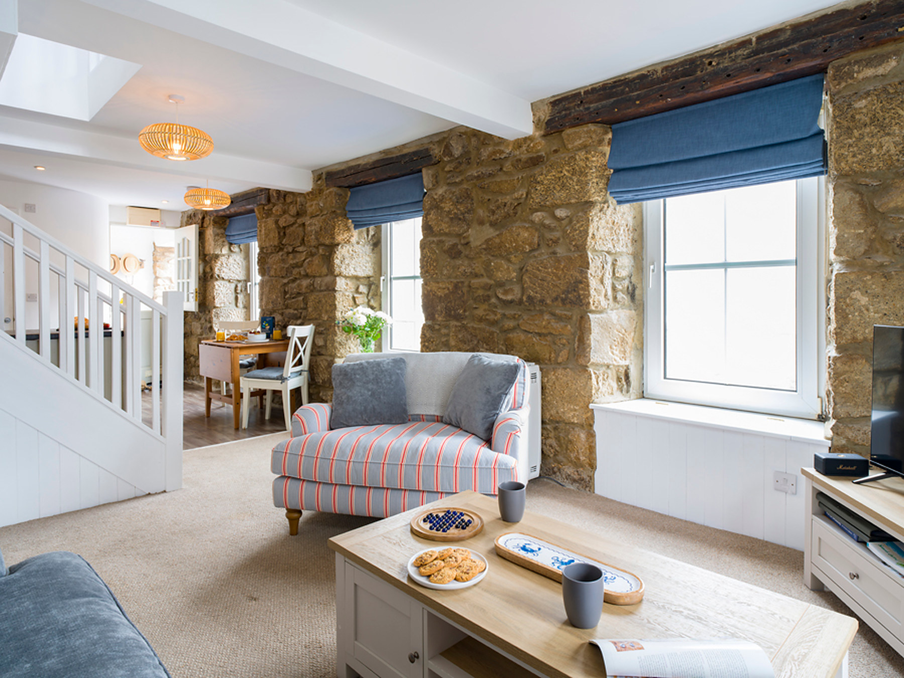 Snuggle chair beside the stone wall, with the staircase and dining table beyond